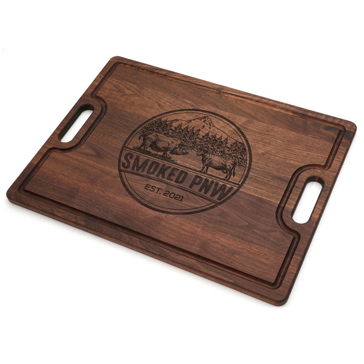Smoked PNW company logo engraved in the center of a Walnut board with cutout handles