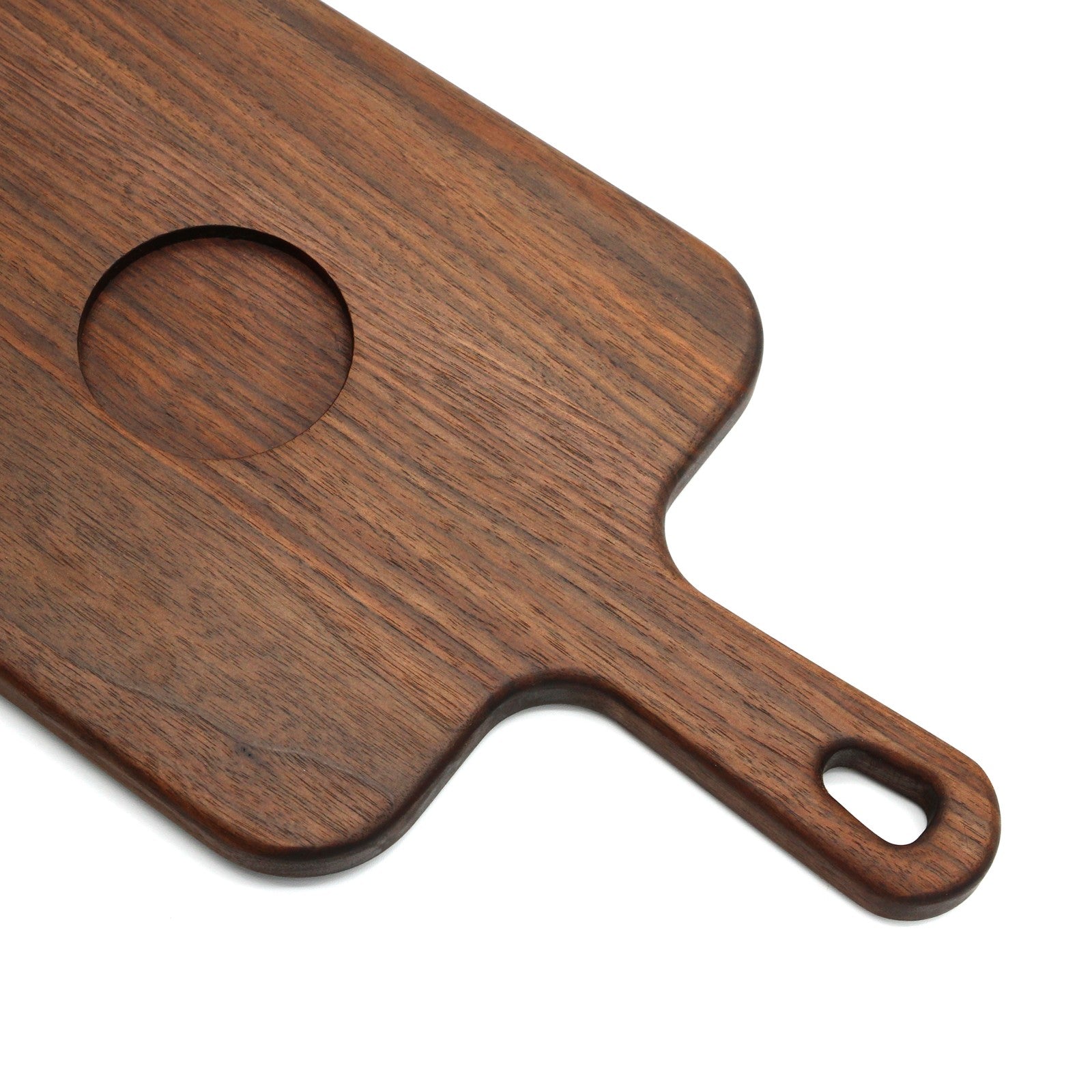Close-up of a walnut serving paddle with a circular bowl recess and cutout handle