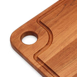 Close-up of the cherry thumb-hole board handle and curved juice groove.