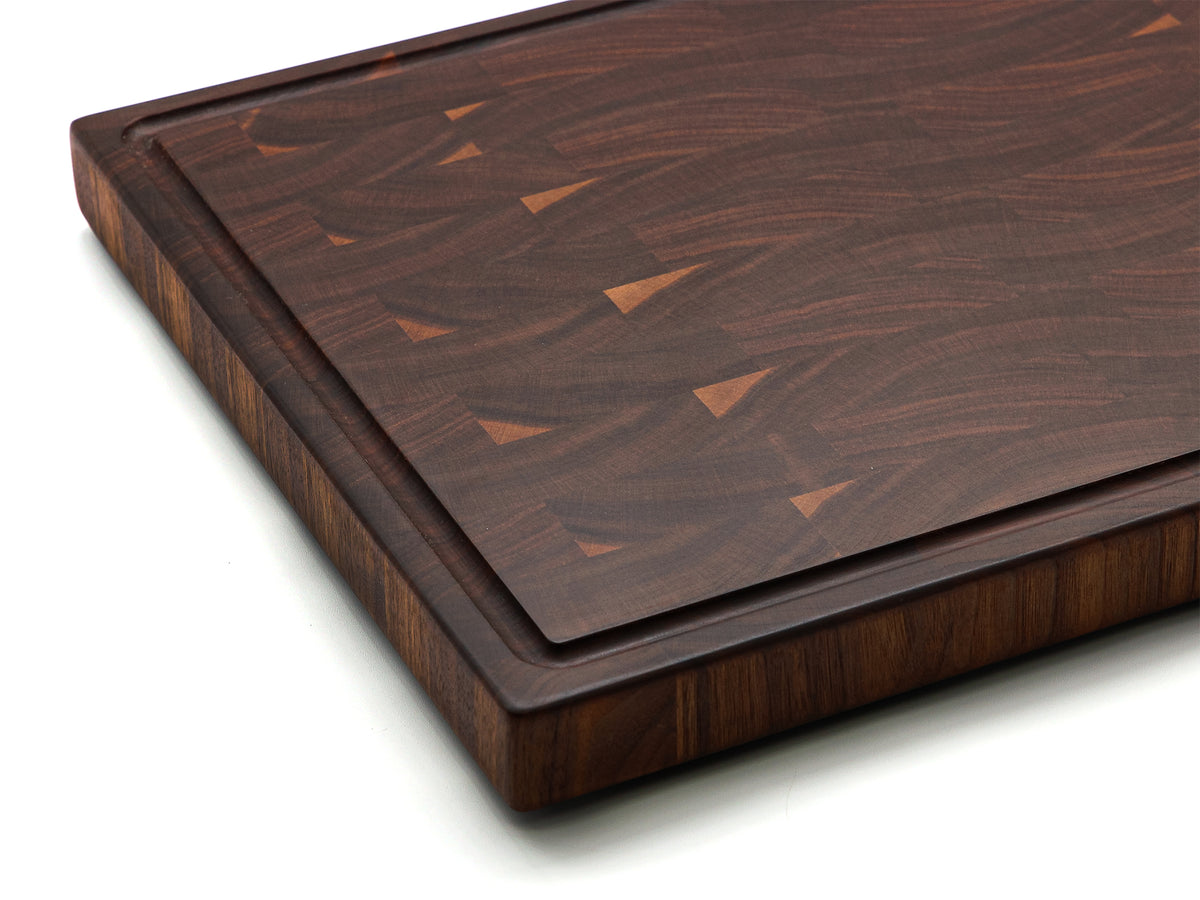 Close-up of the walnut 20 × 15 end-grain cutting board corner, showing the juice groove and thick edge.