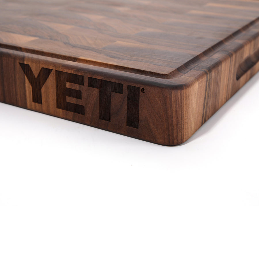Close-up of the YETI logo engraved into the edge of a thick Walnut end-grain board