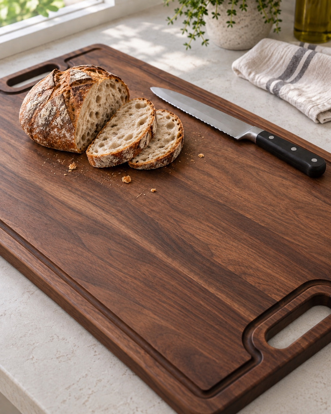 Freshly sliced sourdough on a walnut flat-grain cutting board with a juice groove and cutout handles